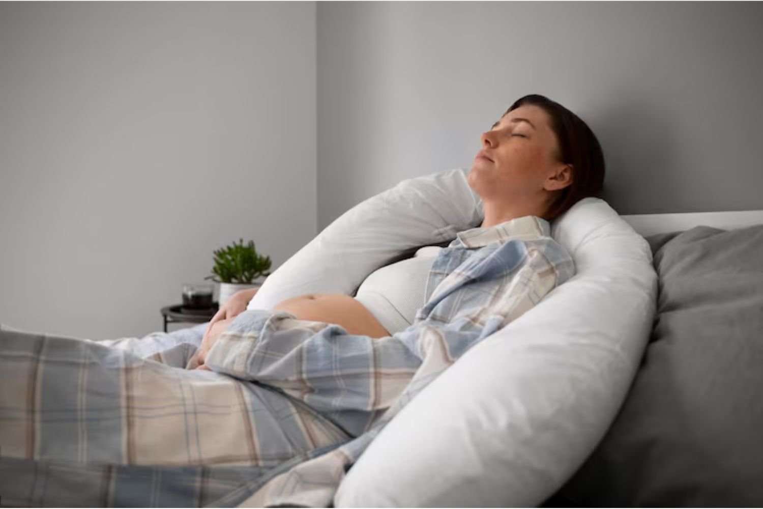 Pregnant woman sleeping on her side with a U-shaped pregnancy pillow to relieve back pain.